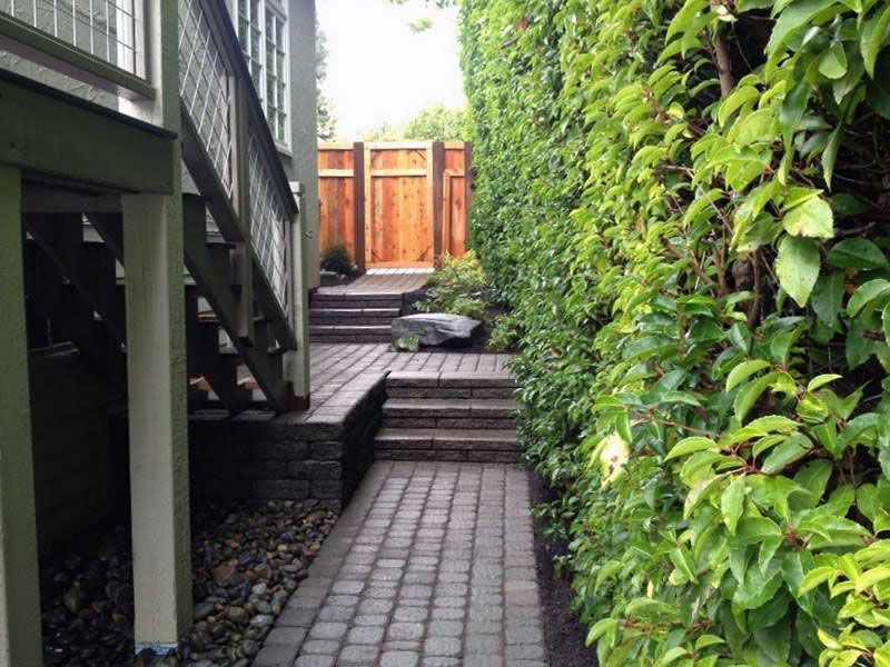 a brick walkway leading to a wooden gate and stairs