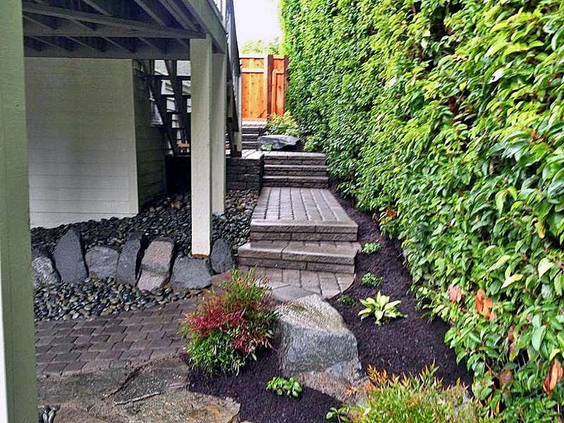 a wooden walkway leading to a deck and stairs in a backyard