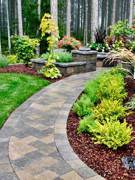 a brick walkway in a garden with trees