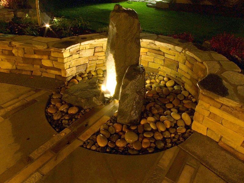 a water fountain is lit up at night in a garden