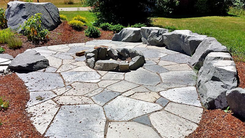 a stone patio with a fire pit in the middle surrounded by rocks