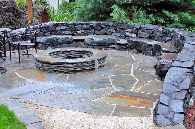 a stone patio with a fire pit in the middle