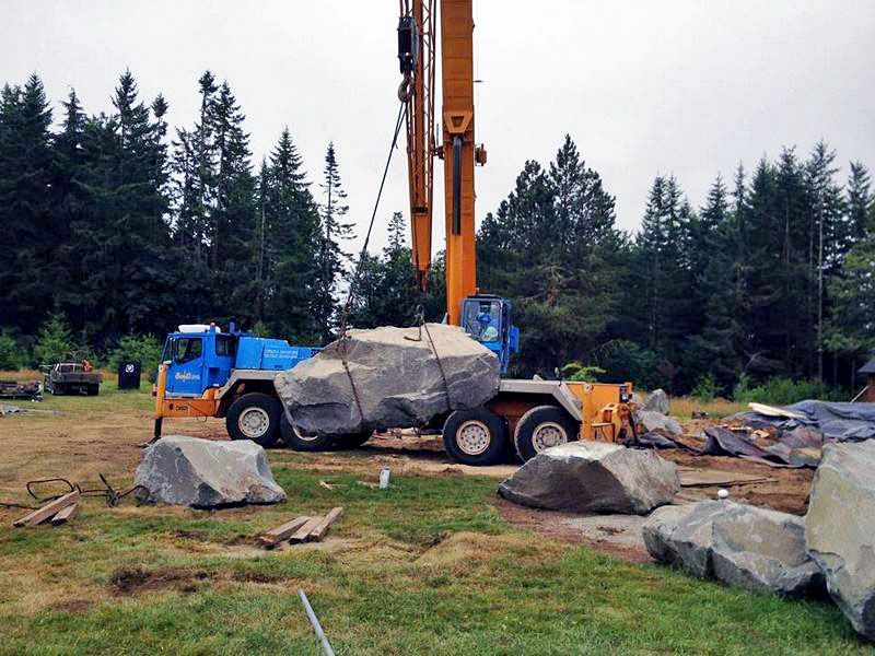 a crane is lifting a large rock in a field