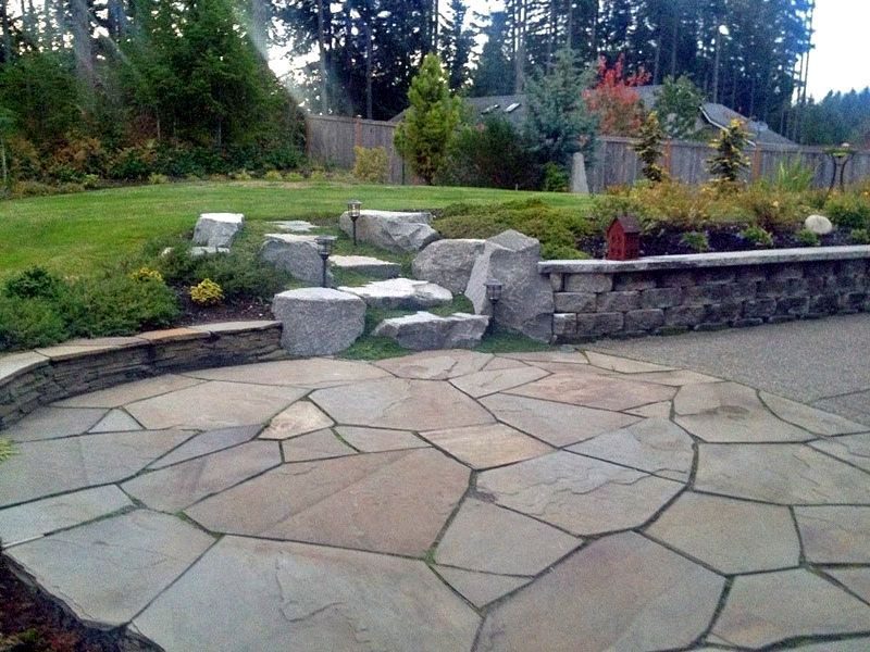 a stone patio in a backyard with trees in the background