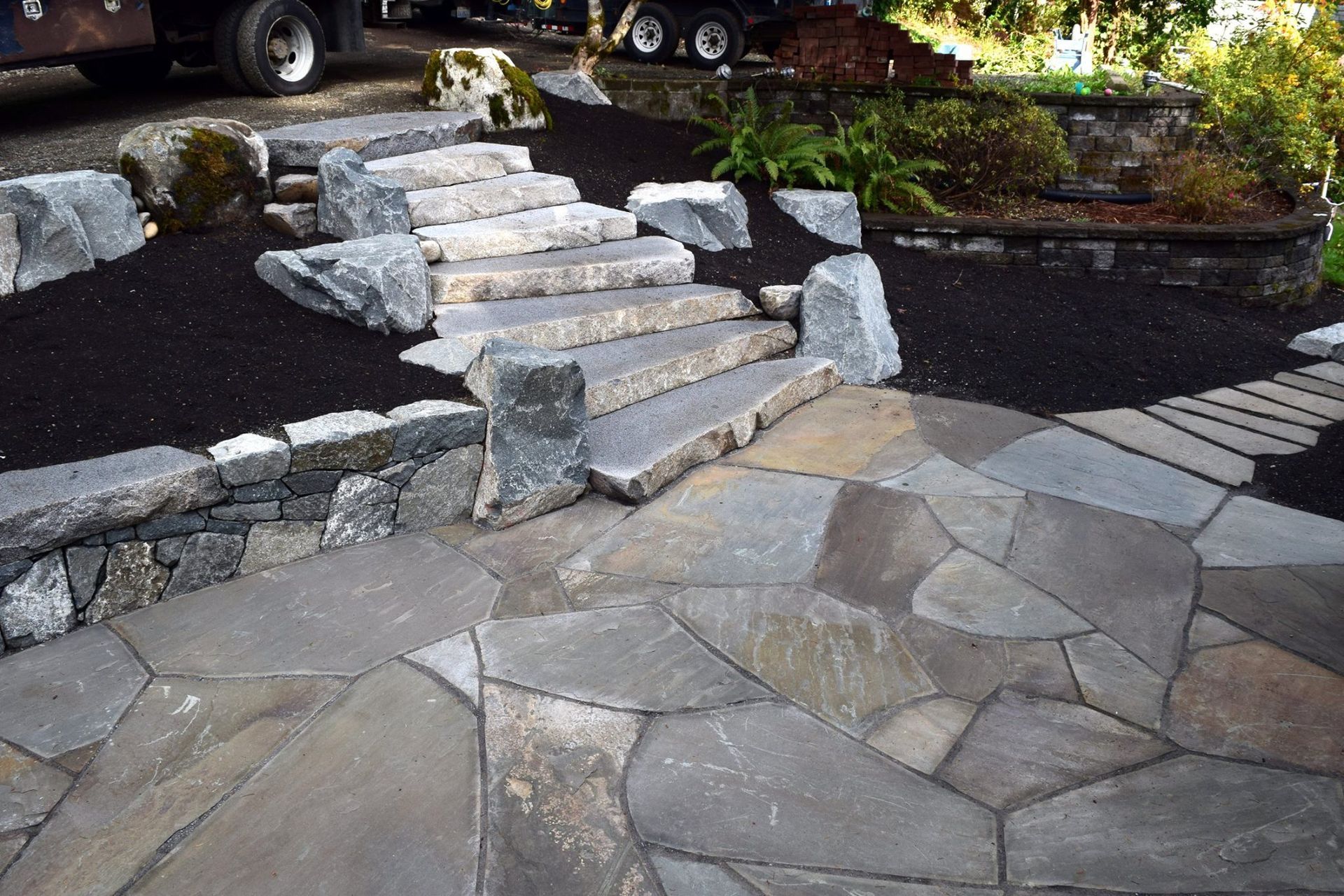 a stone walkway with stairs and a truck in the background