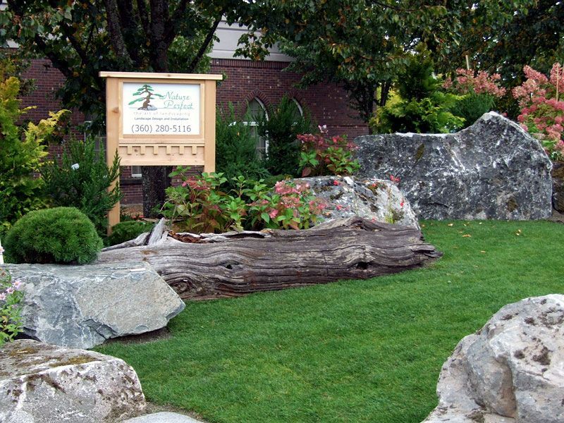 a wooden sign in a garden with a phone number on it