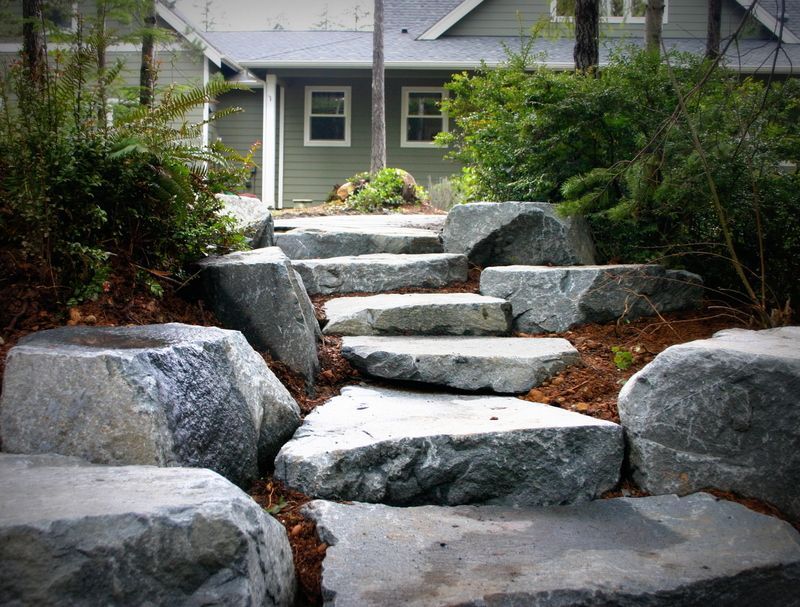 a stone walkway leading to a house in the woods