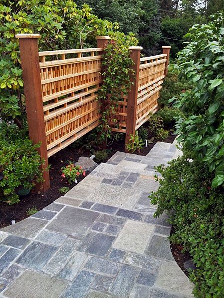 a wooden fence surrounds a stone walkway in a garden