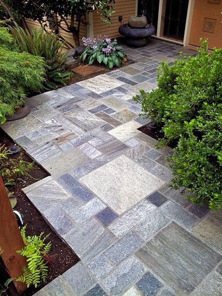 a stone walkway leading to a house with a fountain in the background