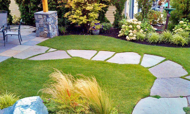 a lush green lawn with a stone walkway in the middle