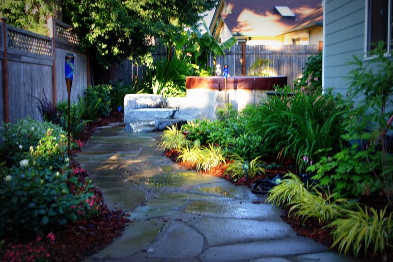 a walkway leading to a house with a hot tub in the backyard