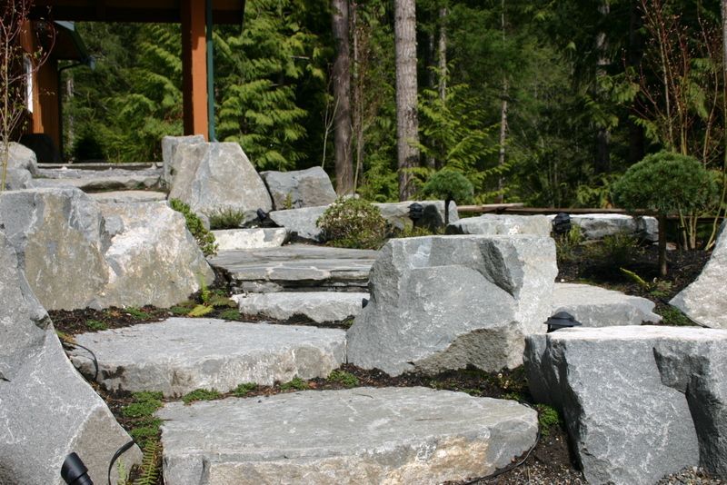 a stone walkway surrounded by large rocks in a forest