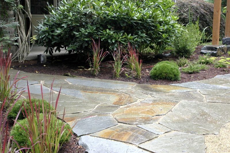 a stone walkway surrounded by plants and bushes in a garden