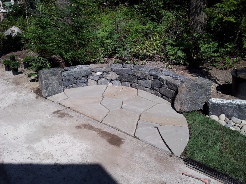 a concrete walkway with a stone wall surrounding it