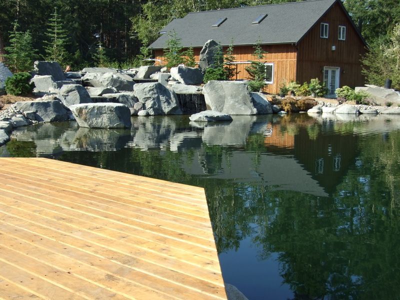 a house is reflected in the water of a pond