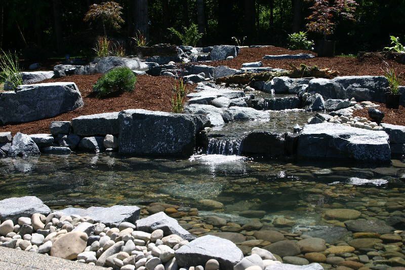 there is a small waterfall in the middle of a pond surrounded by rocks