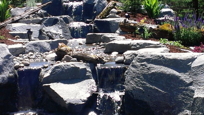 a waterfall surrounded by rocks and plants in a garden