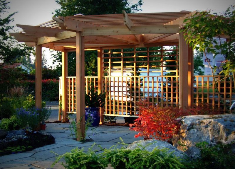 a wooden pergola is in the middle of a garden
