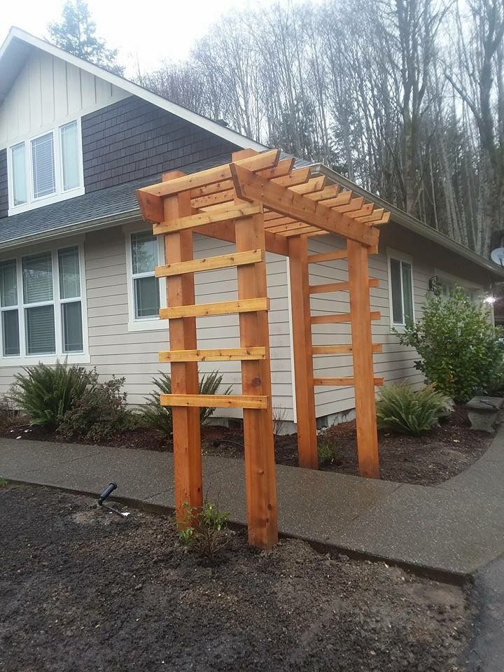 a wooden pergola is in front of a house