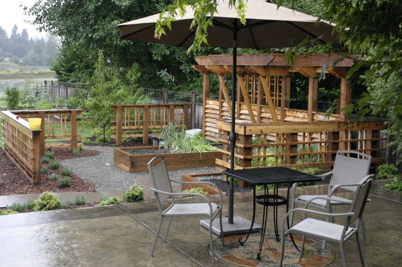 a table and chairs under an umbrella in front of a gazebo