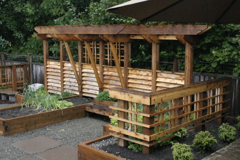 a garden with a wooden pergola and umbrellas