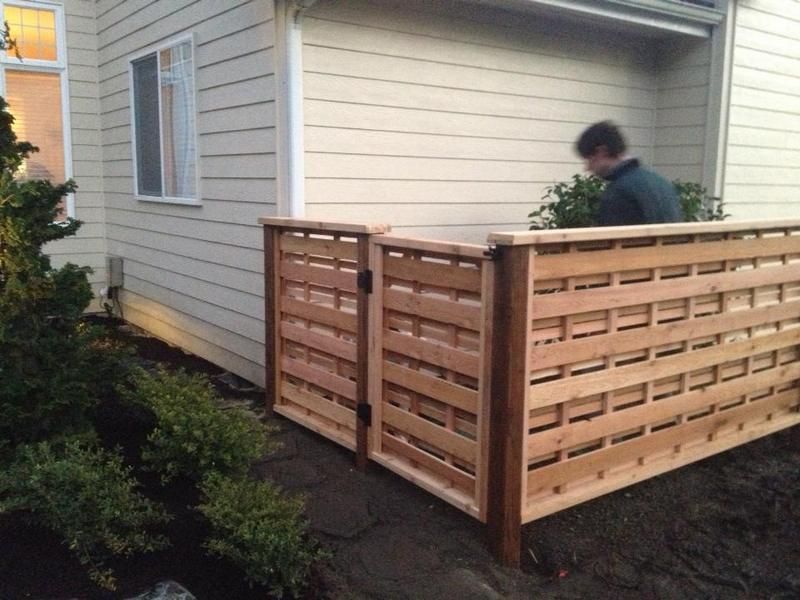 a man is standing next to a wooden fence in front of a house