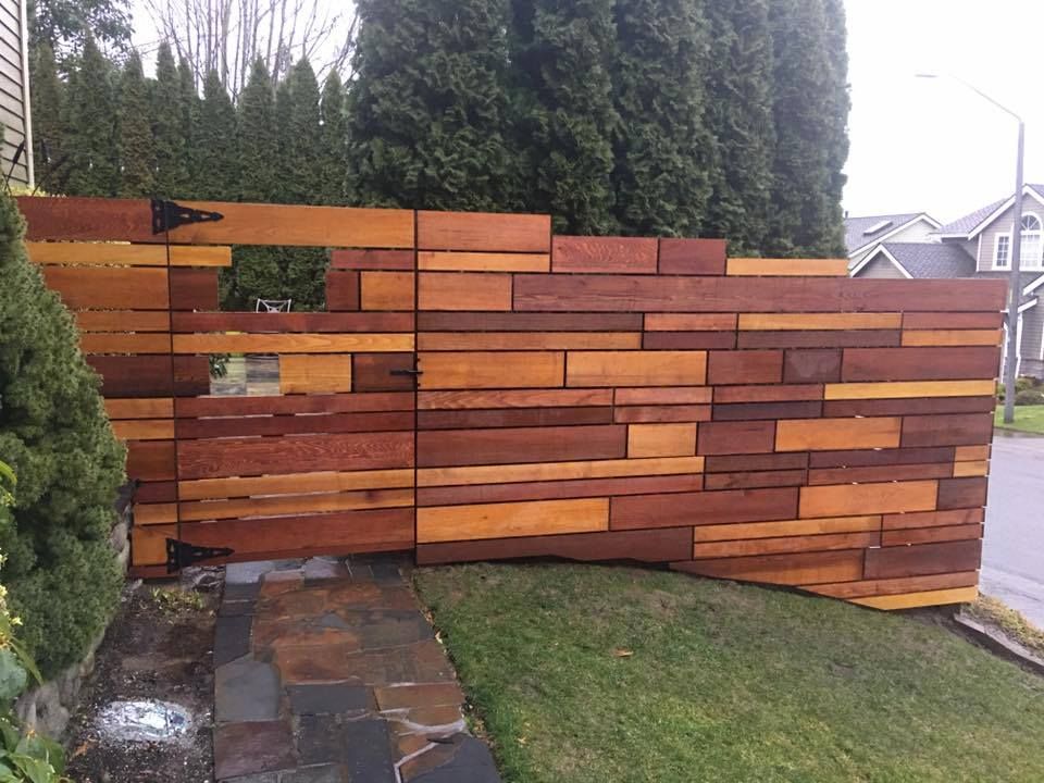 a wooden fence is sitting on top of a lush green lawn in front of a house