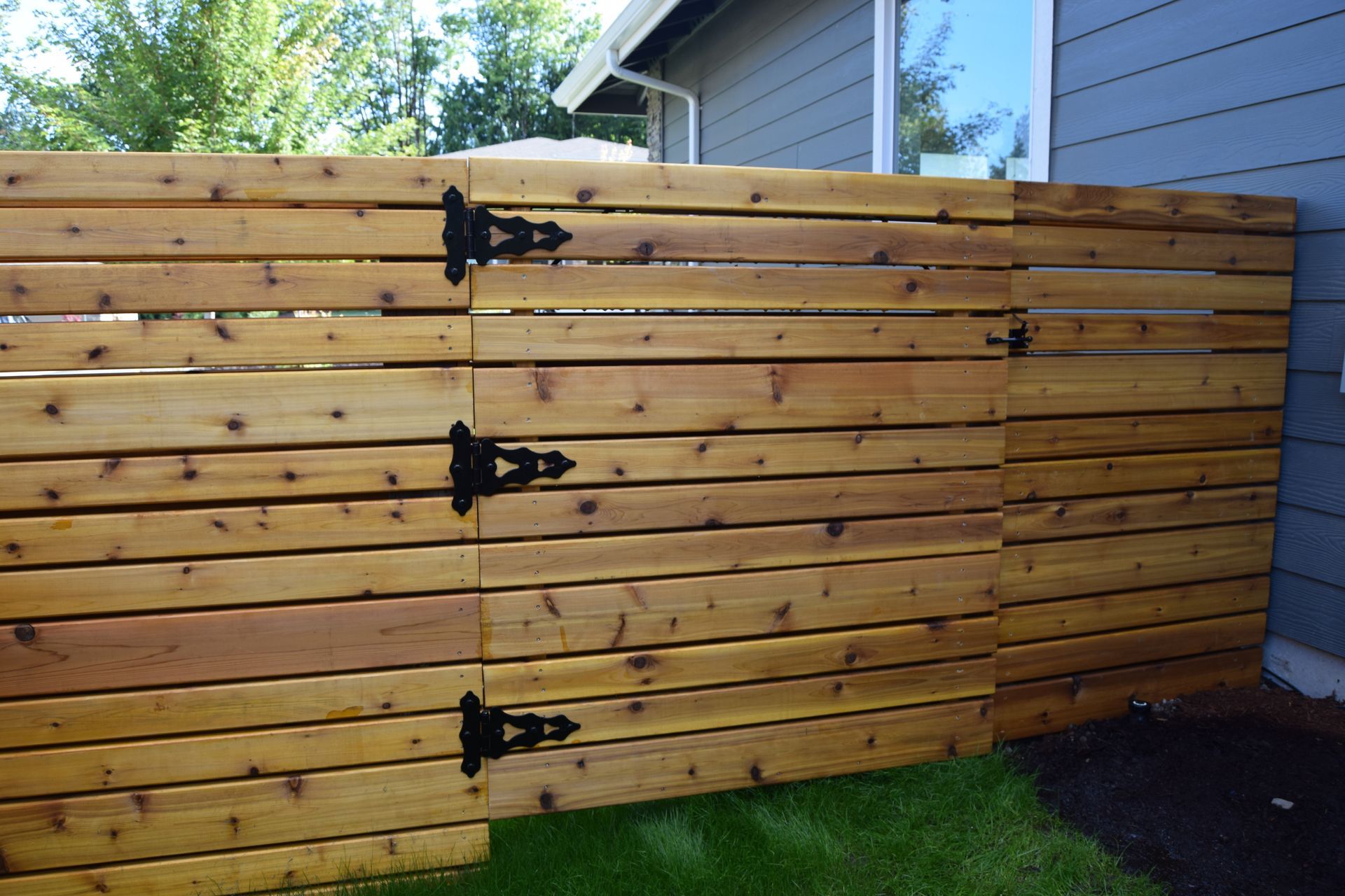 a wooden fence with black hinges is in front of a house