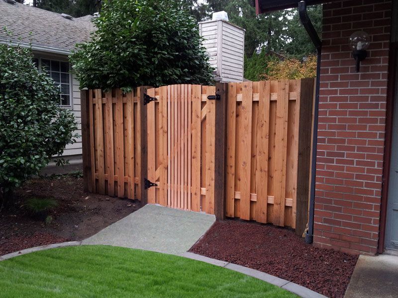 a wooden fence with a gate in front of a brick house