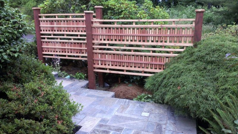 a wooden fence surrounds a stone walkway in a garden