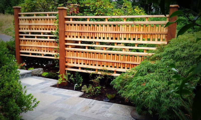 a wooden fence is surrounded by trees and bushes in a garden