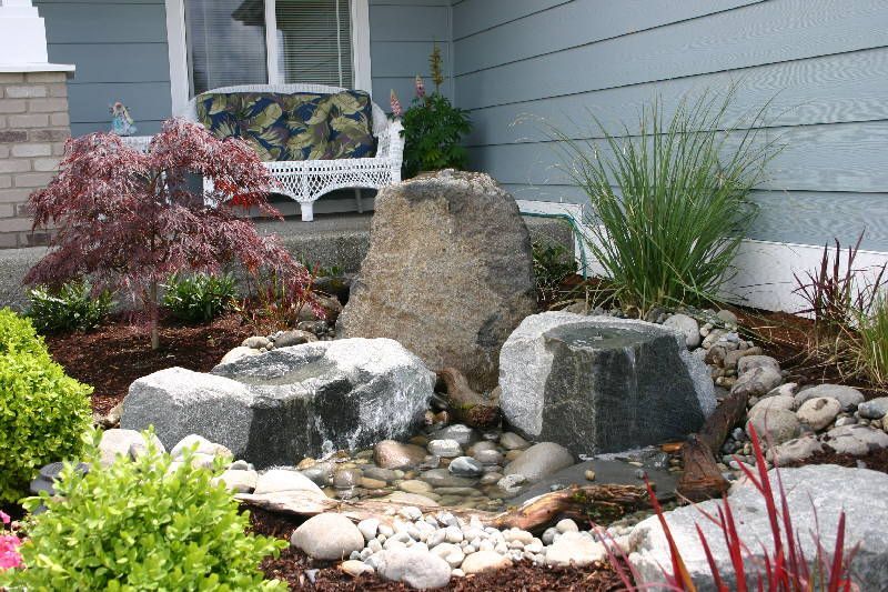 A garden with rocks and plants in front of a house