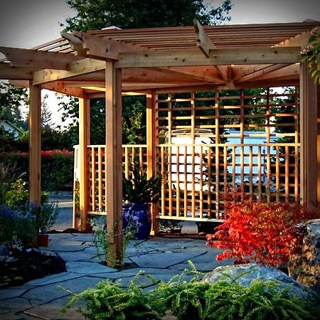 A wooden pergola is surrounded by potted plants and trees