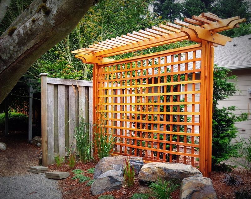 A wooden pergola with a fence in the background