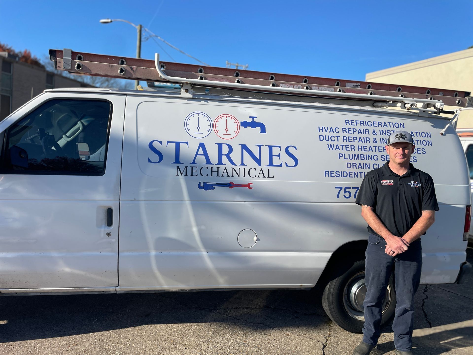 Man stands by a white Starne's Mechanical van with a ladder on top. The man wears a dark uniform.