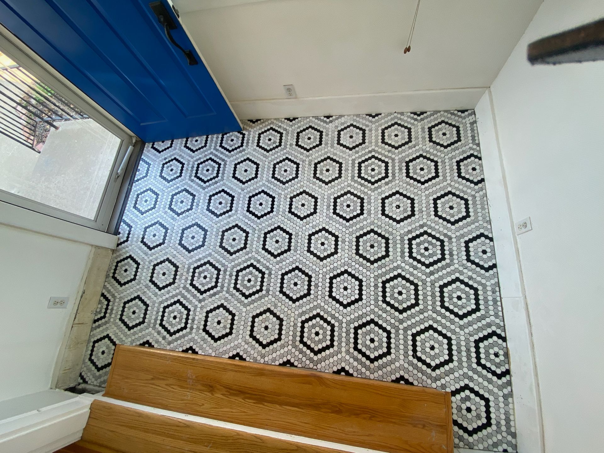 Wall with honeycomb tile pattern; blue door; wooden boards in foreground.