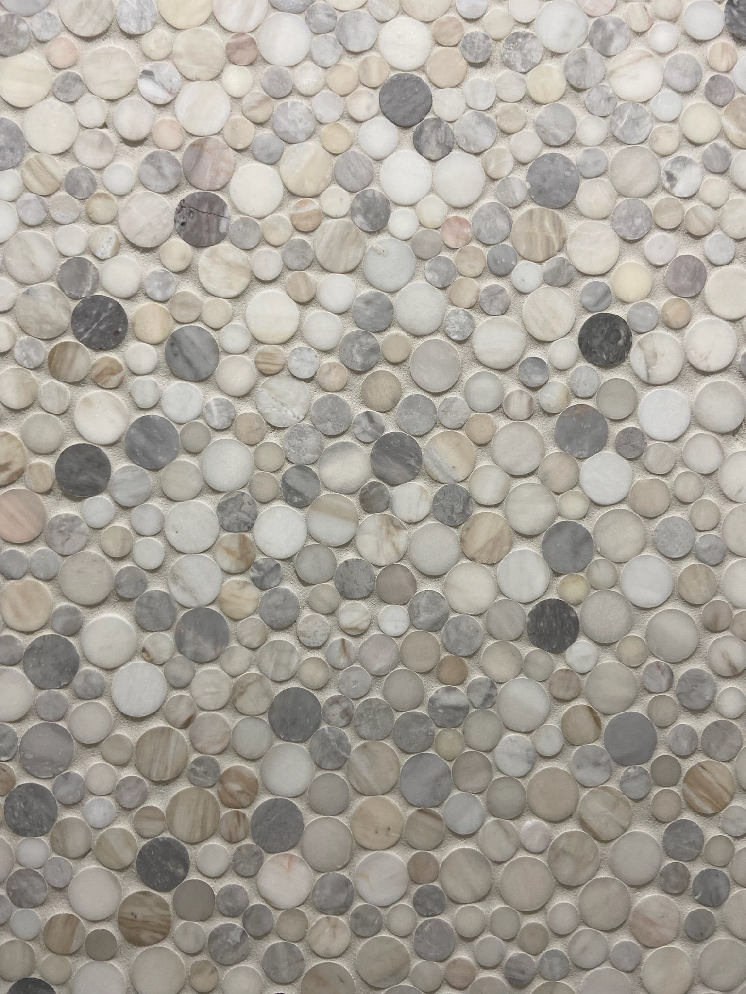 Circular stone tile mosaic with shades of gray, beige, and white.
