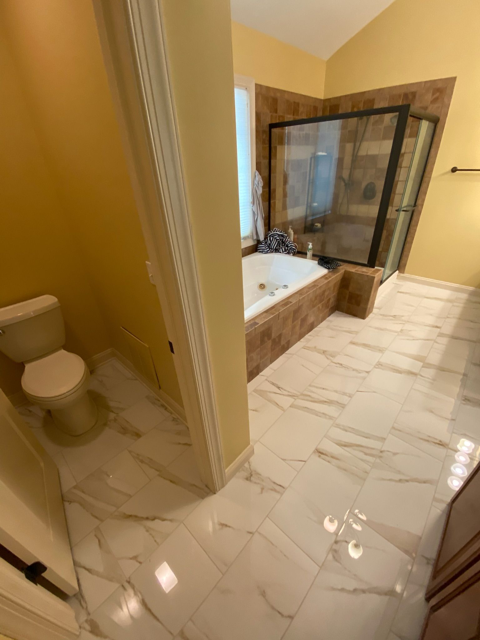 Bathroom with white marble floor, a jacuzzi, and a glass shower.