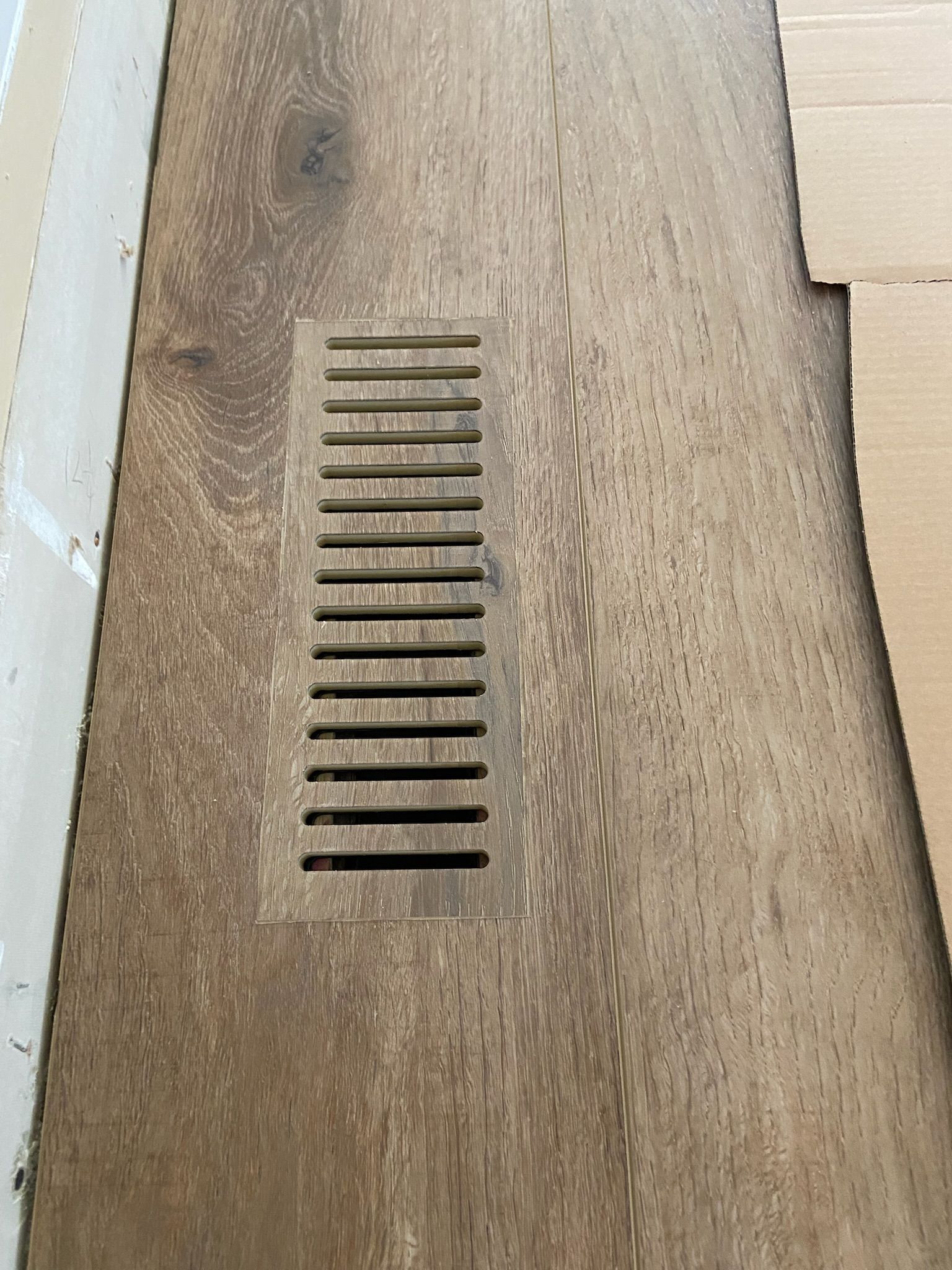 Wooden floor with a rectangular vent cover.