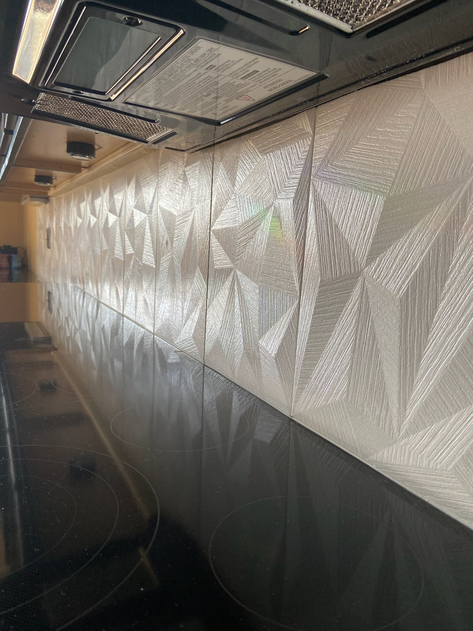 Inside of a food truck. Silver insulation covers the wall. Shiny black counter in foreground.