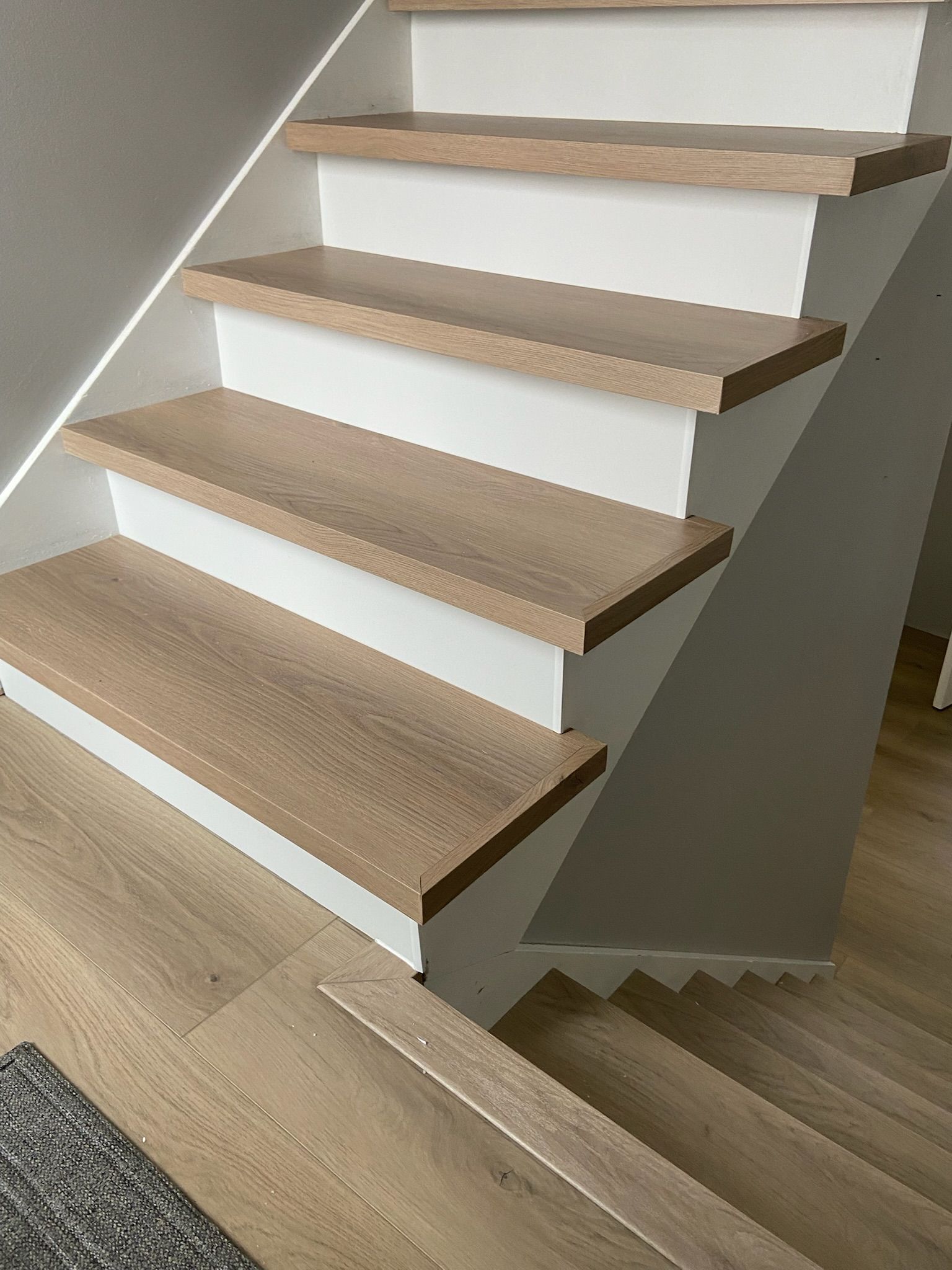 Staircase with wooden steps and white risers. The staircase leads upwards.
