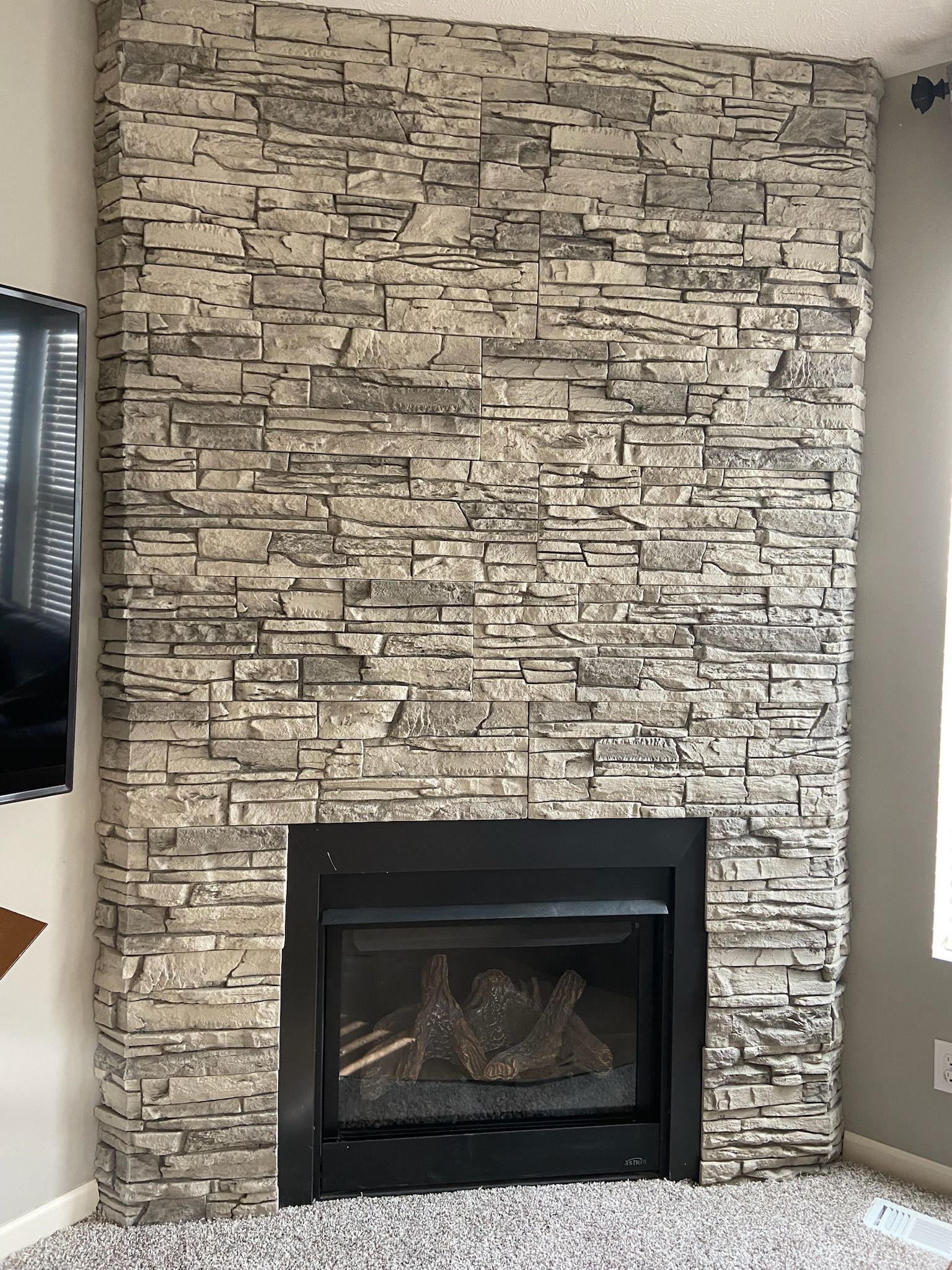 Fireplace with black surround, gray stone wall.