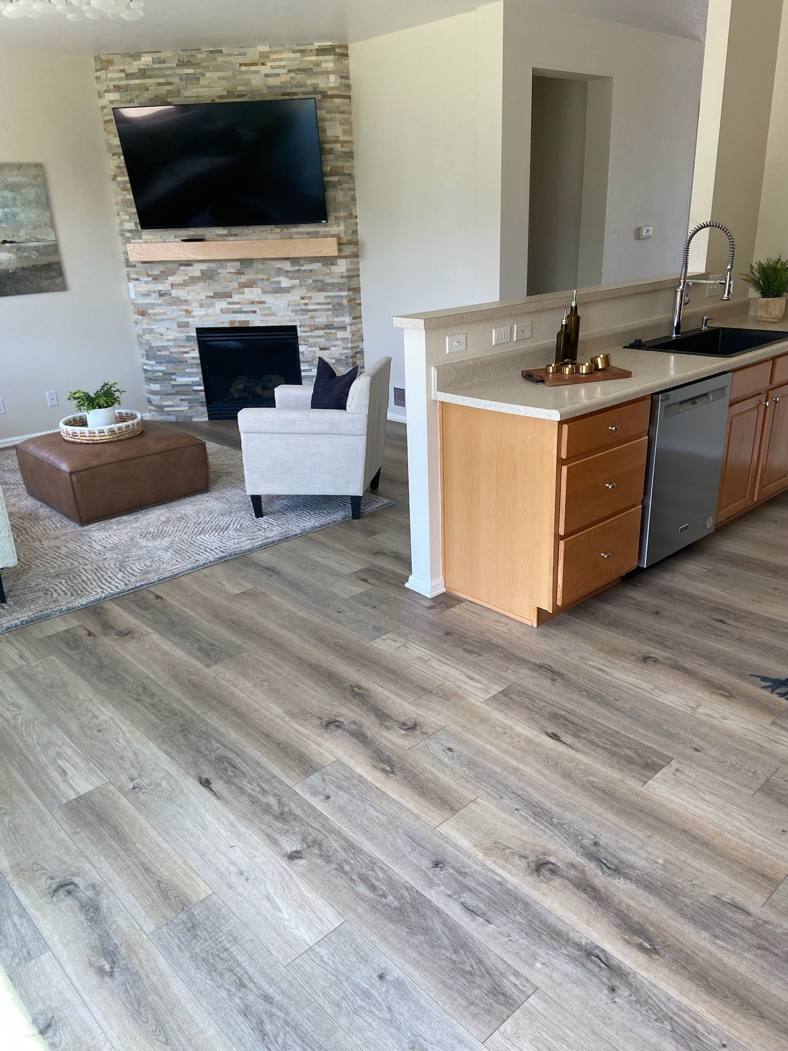 Living room with fireplace, television, and kitchen with wood cabinets and stainless steel appliances.