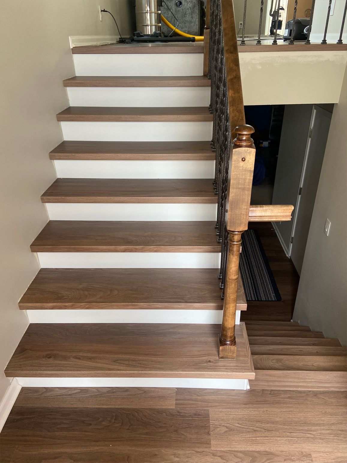Indoor staircase with dark wood steps, white risers, and a wooden banister beside a hallway opening.