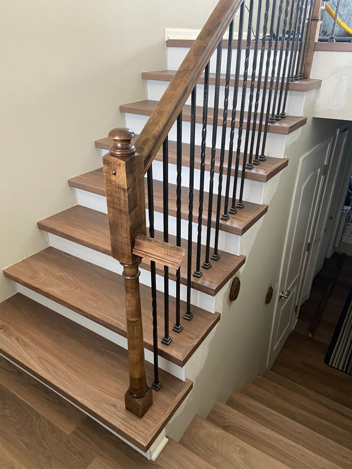 Wooden staircase with white treads, black balusters, and a carved brown handrail indoors