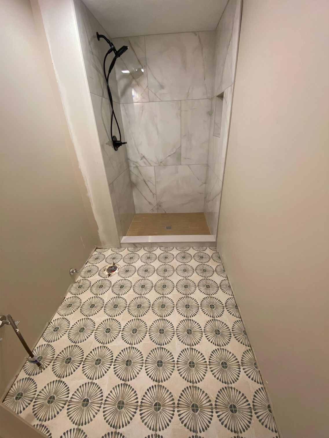 Small bathroom with patterned tile floor and marble shower stall.