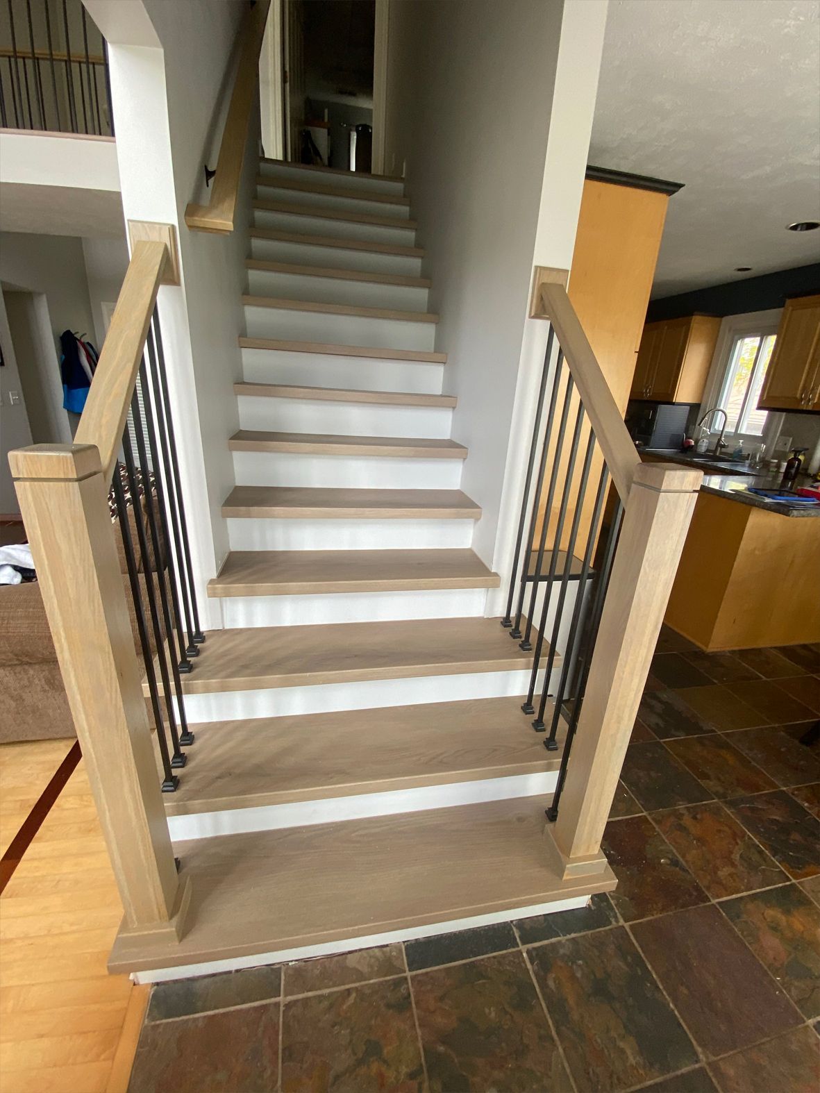 Indoor staircase with white steps, black railings, and tile floor in a home interior