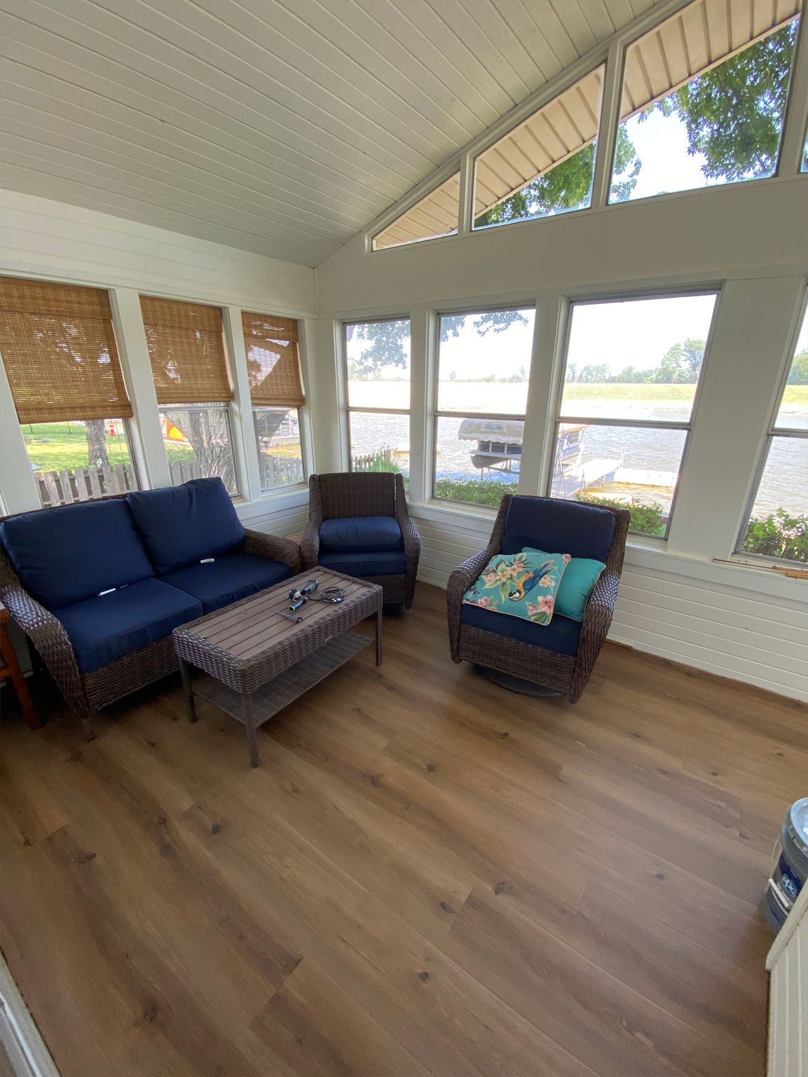 Sunroom with blue sofa, patterned chair, ottoman, and large windows overlooking water