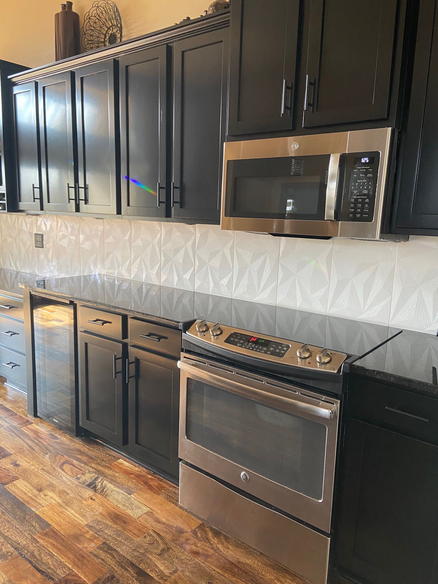 Black kitchen cabinets with stainless steel appliances and white tile backsplash.
