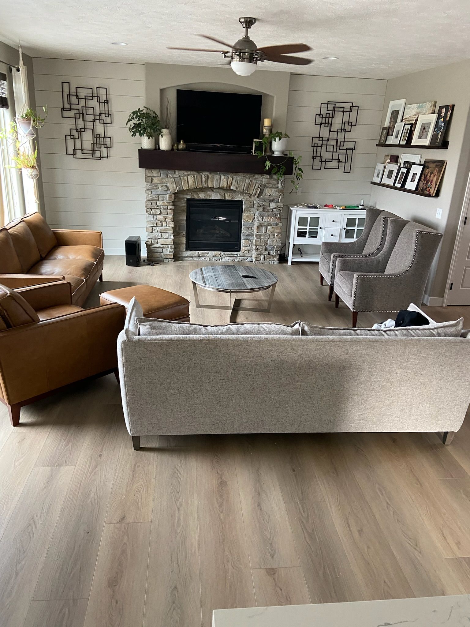 Living room with fireplace, TV, and assorted furniture. Neutral tones, light wood floors, decorative wall art.